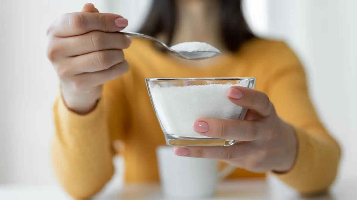 Woman adding sugar to coffee